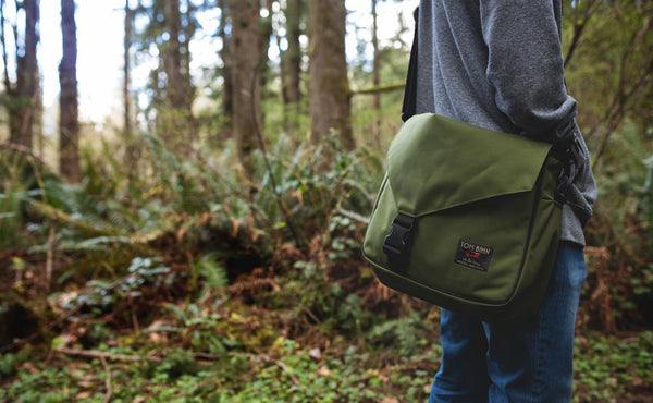 A person carrying a Maker's Bag in the woods.